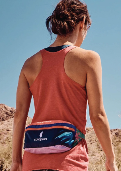 Image showcasing a woman hiking with a Cotopaxi Bataan Hip Pack.